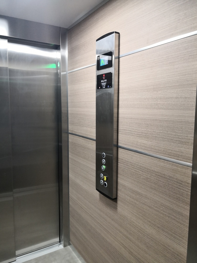 intérieur d'un ascenseur avec centre de contrôle et habillage effet bois